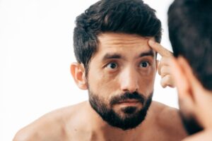 Man inspecting forehead wrinkles in mirror